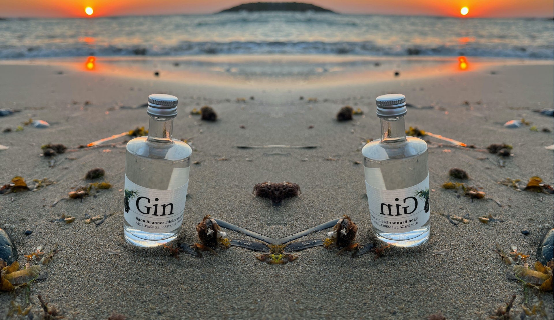 50ml Miniflasche mit Gin der Destillerie Brunner im Sand am Meer von Kreta während eines Sonnenuntergangs.