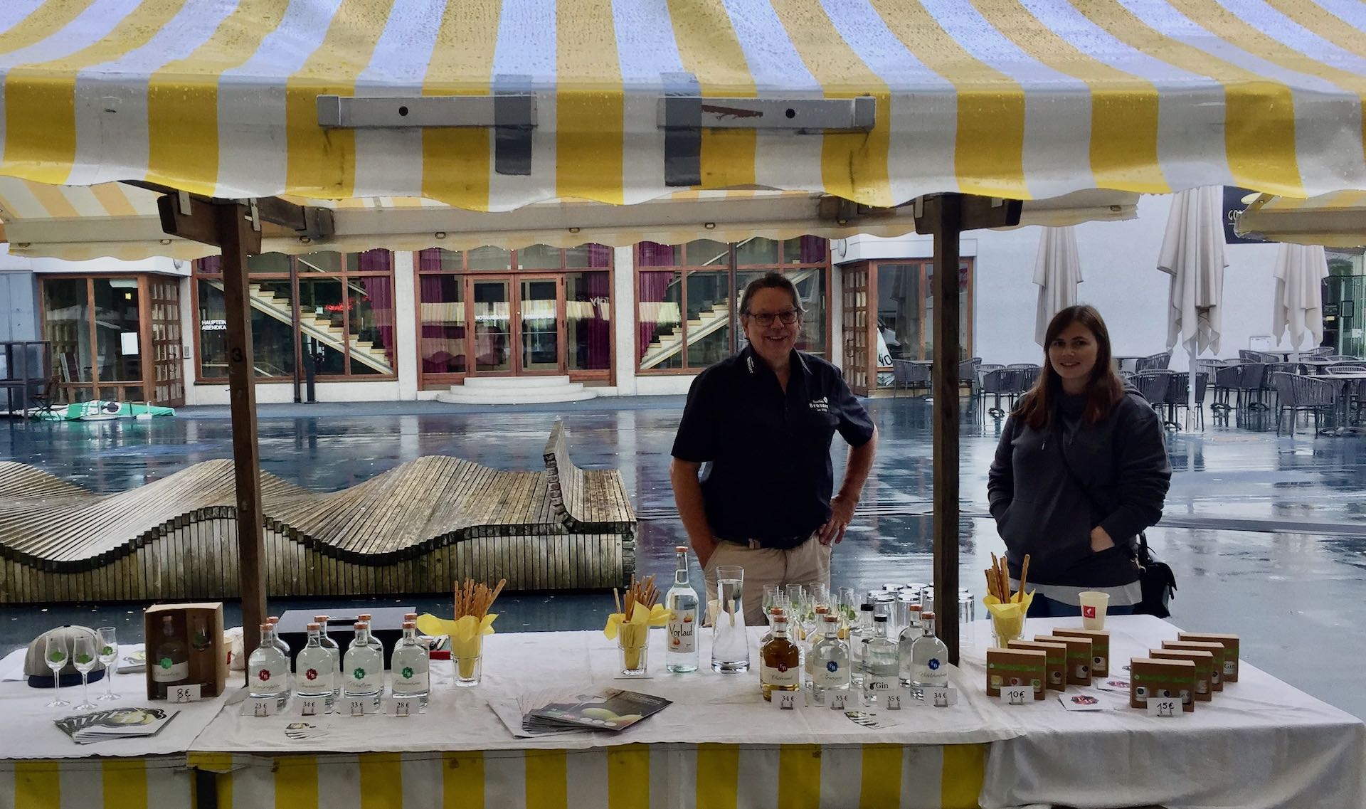 Foto von Egon Brunner und Nina als sie beim Kulinarik am Markt in Lusteanu dem Wetter trotzen und in die Kamera lächeln.