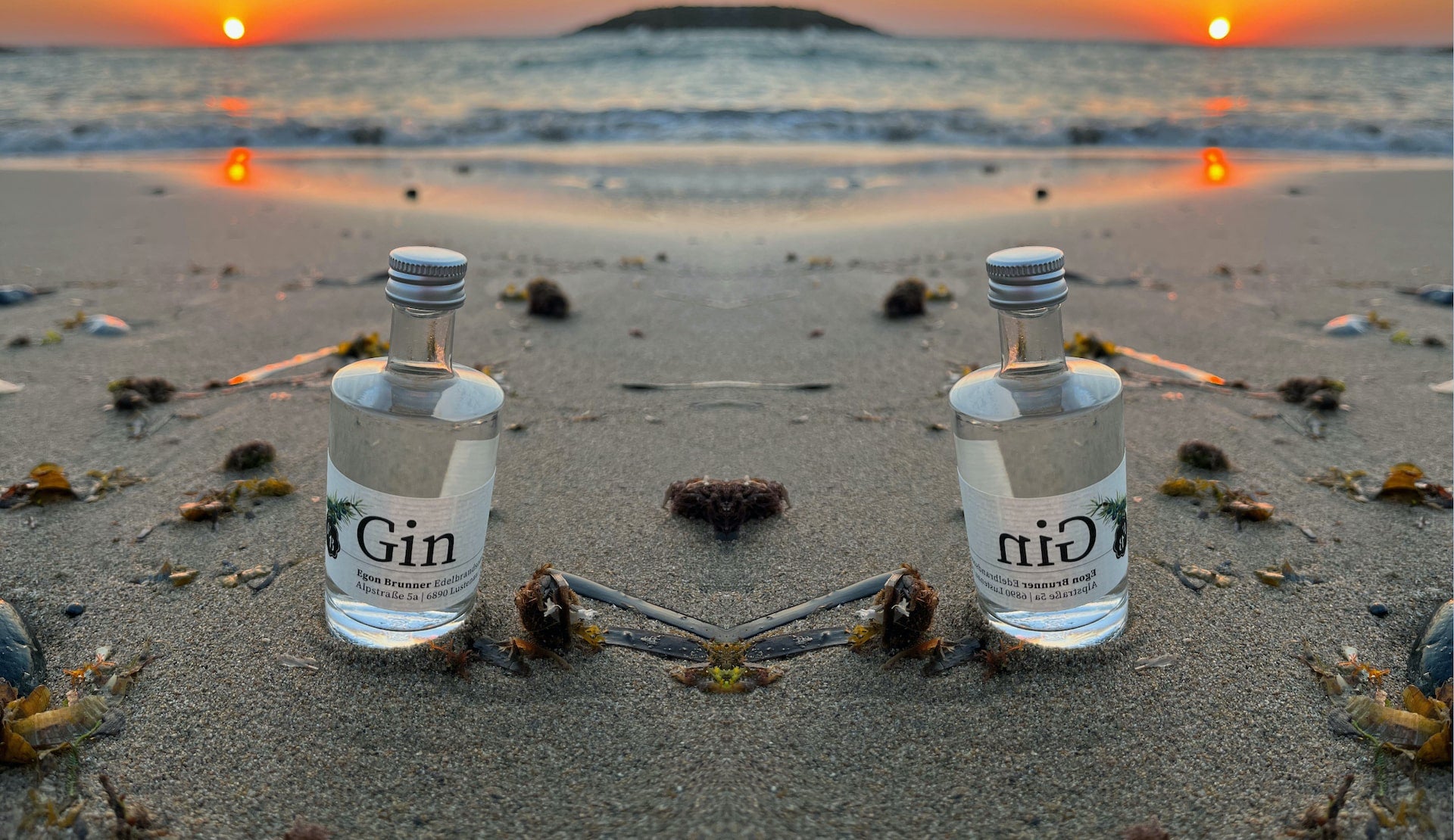 50ml Miniflaschen mit Gin der Destillerie Brunner im Sand am Meer von Kreta während eines Sonnenuntergangs.