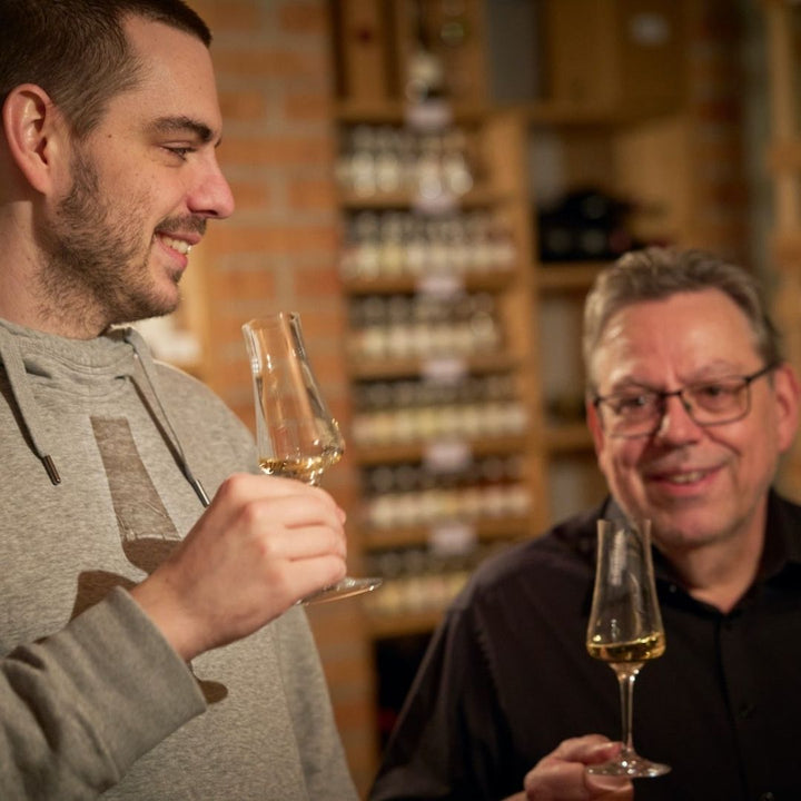 Daniel und Egon der Destillerie Brunner lächelnd beim Verkosten von ihrem ausgezeichneten Birnenbrand Alte Sorten aus Vorarlberg.